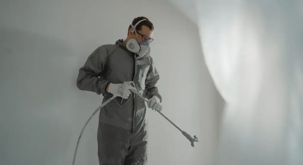 Artisan qui peint à l'aide d'un pulvérisateur de peinture haute pression