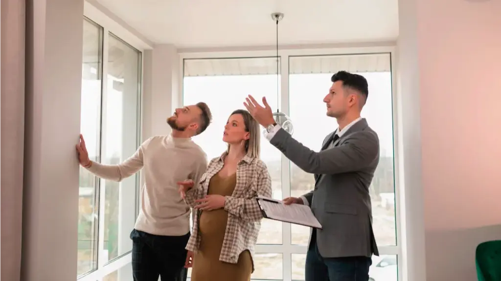 Agent immobilier qui fait visiter un appartement à vendre à un jeune couple